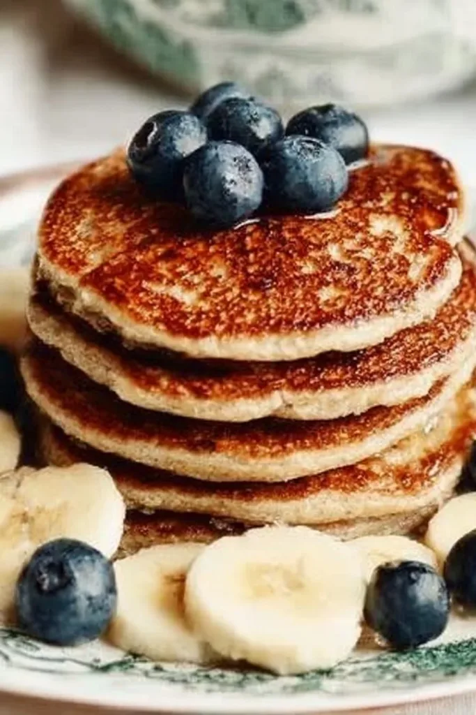 Fluffy banana pancakes topped with fresh bananas and syrup on a plate