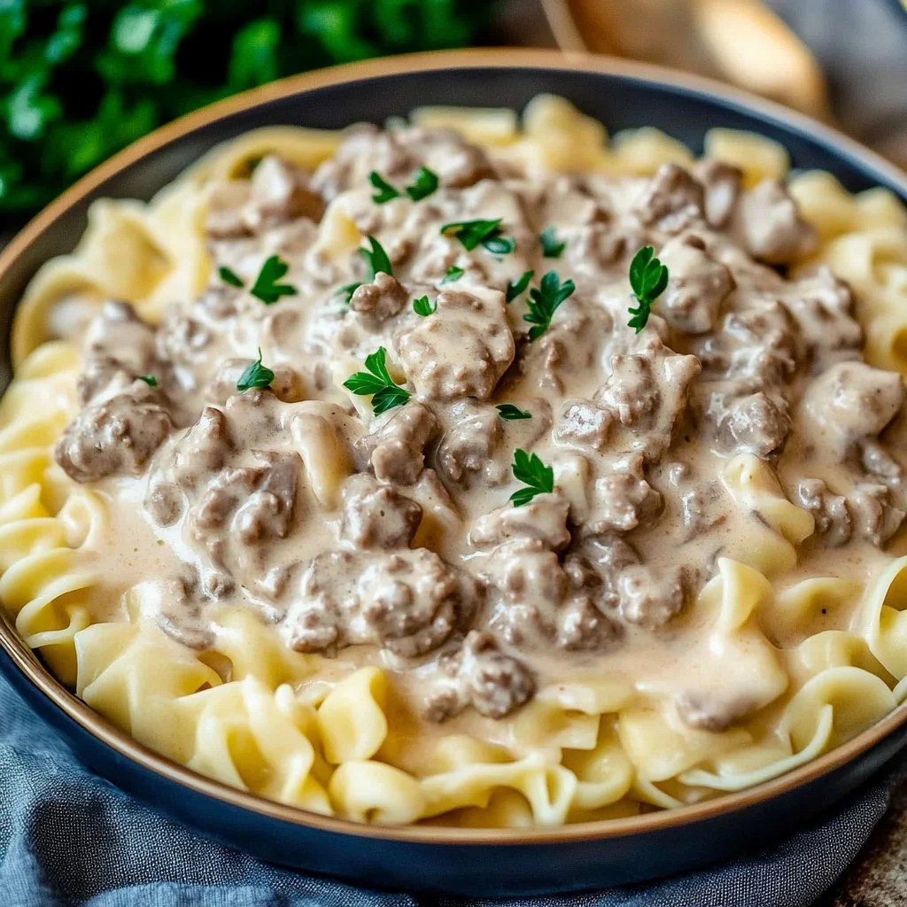 Dish of ground turkey stroganoff served with noodles and garnished with herbs